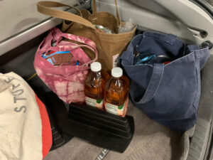 cloth bags of groceries, and 2 bottles of apple juice not in a bag, in the hatchback of a car