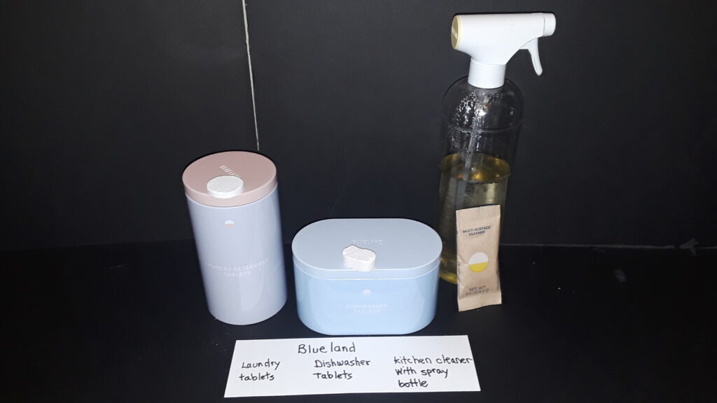 Blueland products: laundry tablets in metal box, dishwasher tablets in metal box, kitchen cleaner dissolved in spray bottle